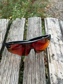GORPED Strider sunglasses with the Ember lens on a weathered wooden bench beside green plants