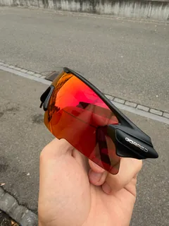 Side view of GORPED Strider sunglasses in a hand, showing the Ember lens and the GORPED logo on the temple