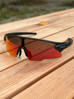 GORPED Strider sunglasses with the Ember lens on a light wooden table, seen at an angle from the front
