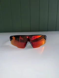 Front view of Ember sunglasses on a pale table in front of a green wall