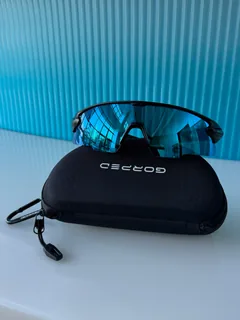 Front view of Glacier sunglasses on a GORPED case in front of blue glass
